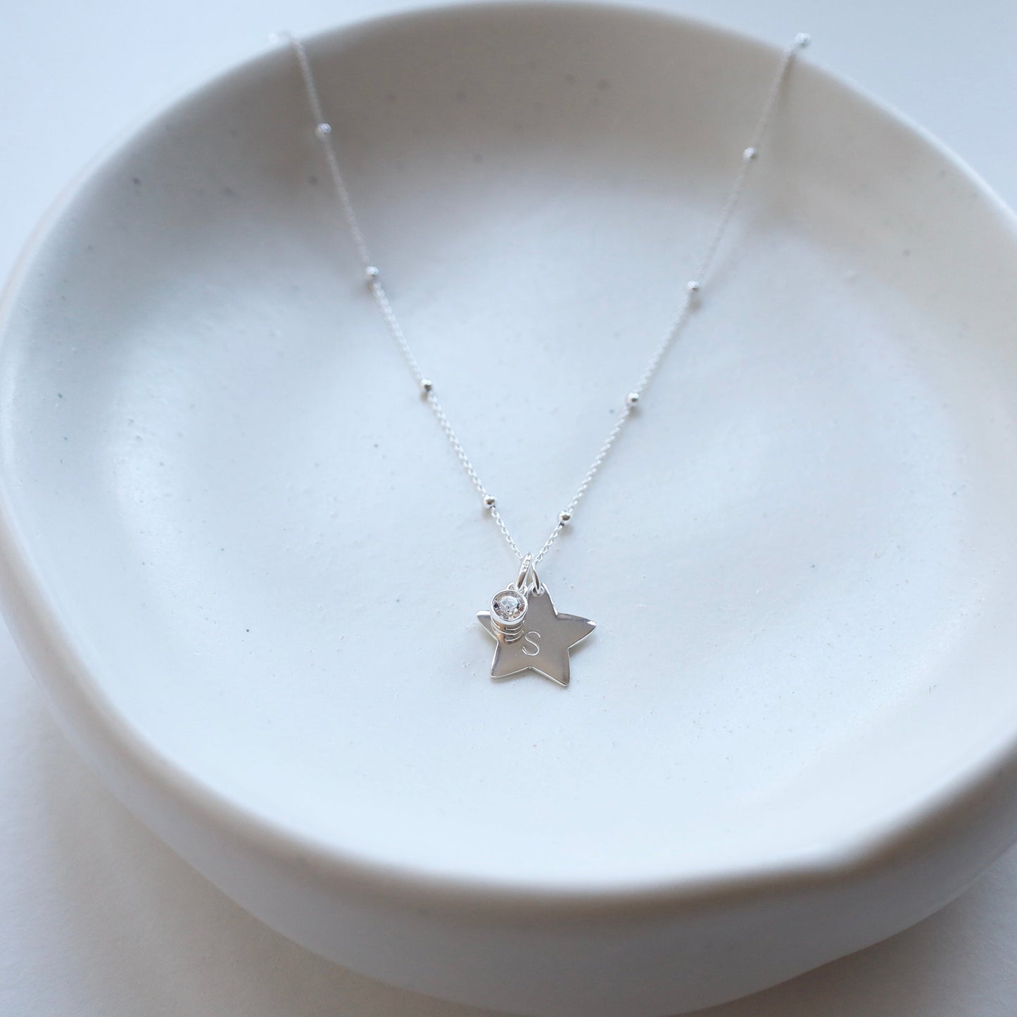 Silver star-shaped pendant necklace on a white dish