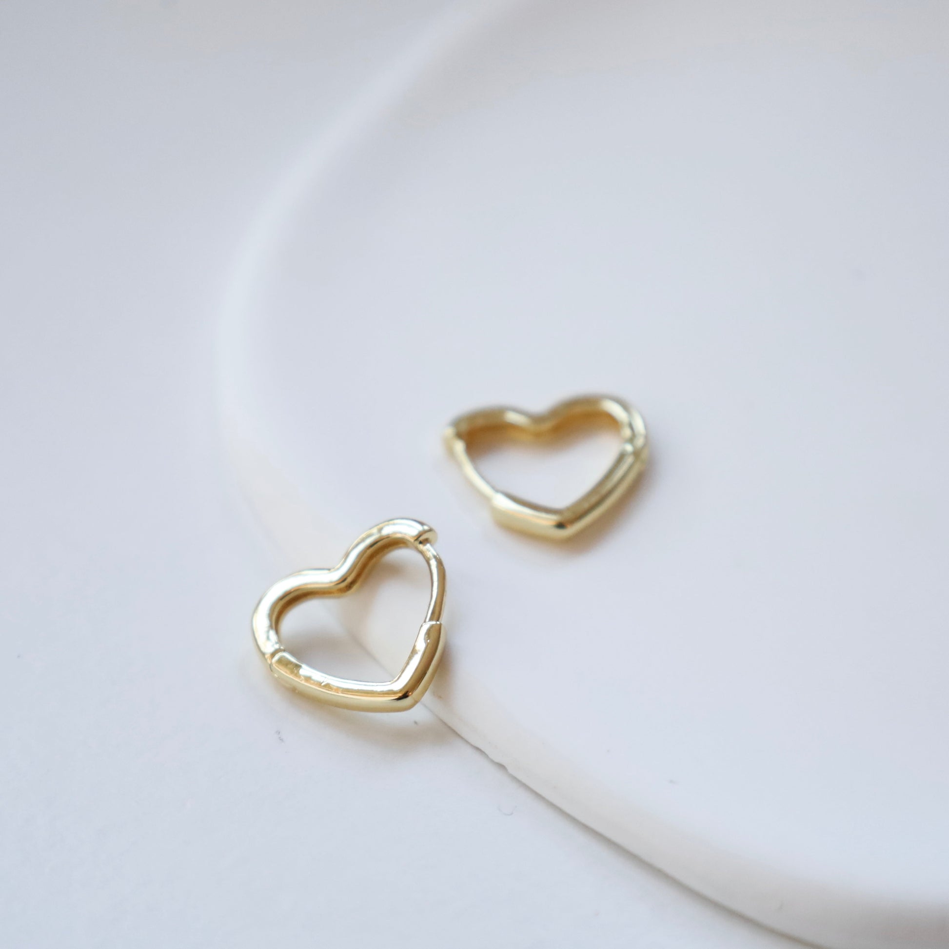 Gold heart-shaped earrings on a light background