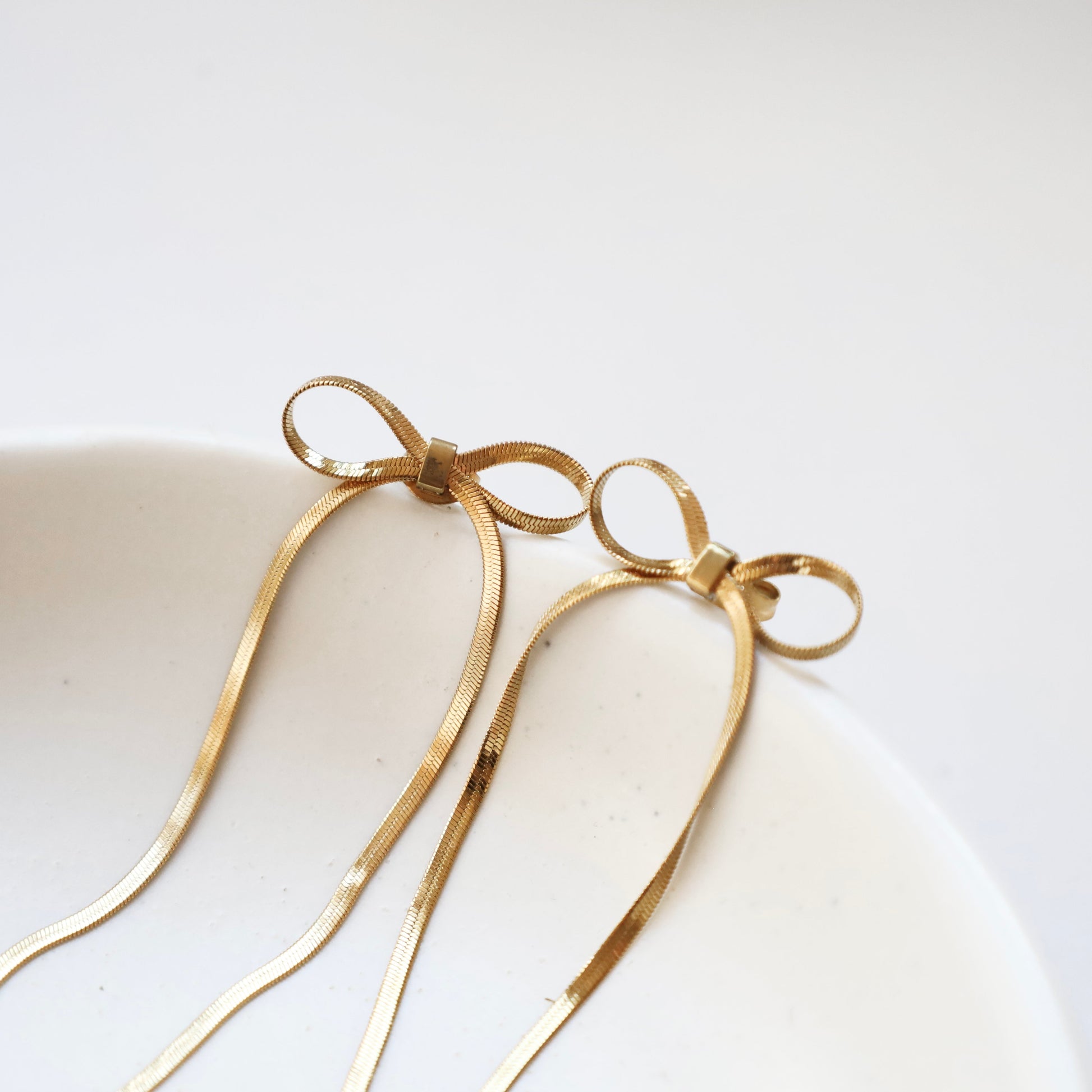 Gold bow-shaped earrings on a white background