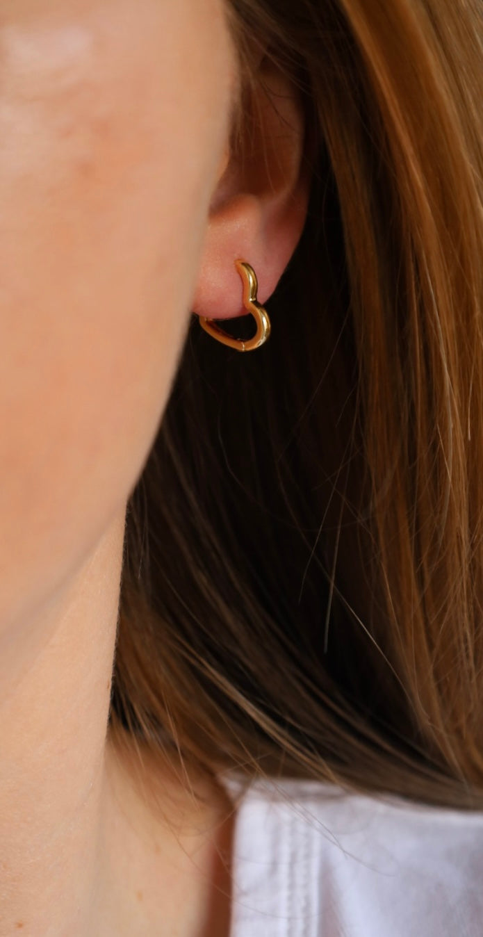 Close-up of a person wearing a gold hoop earring with a blurred background