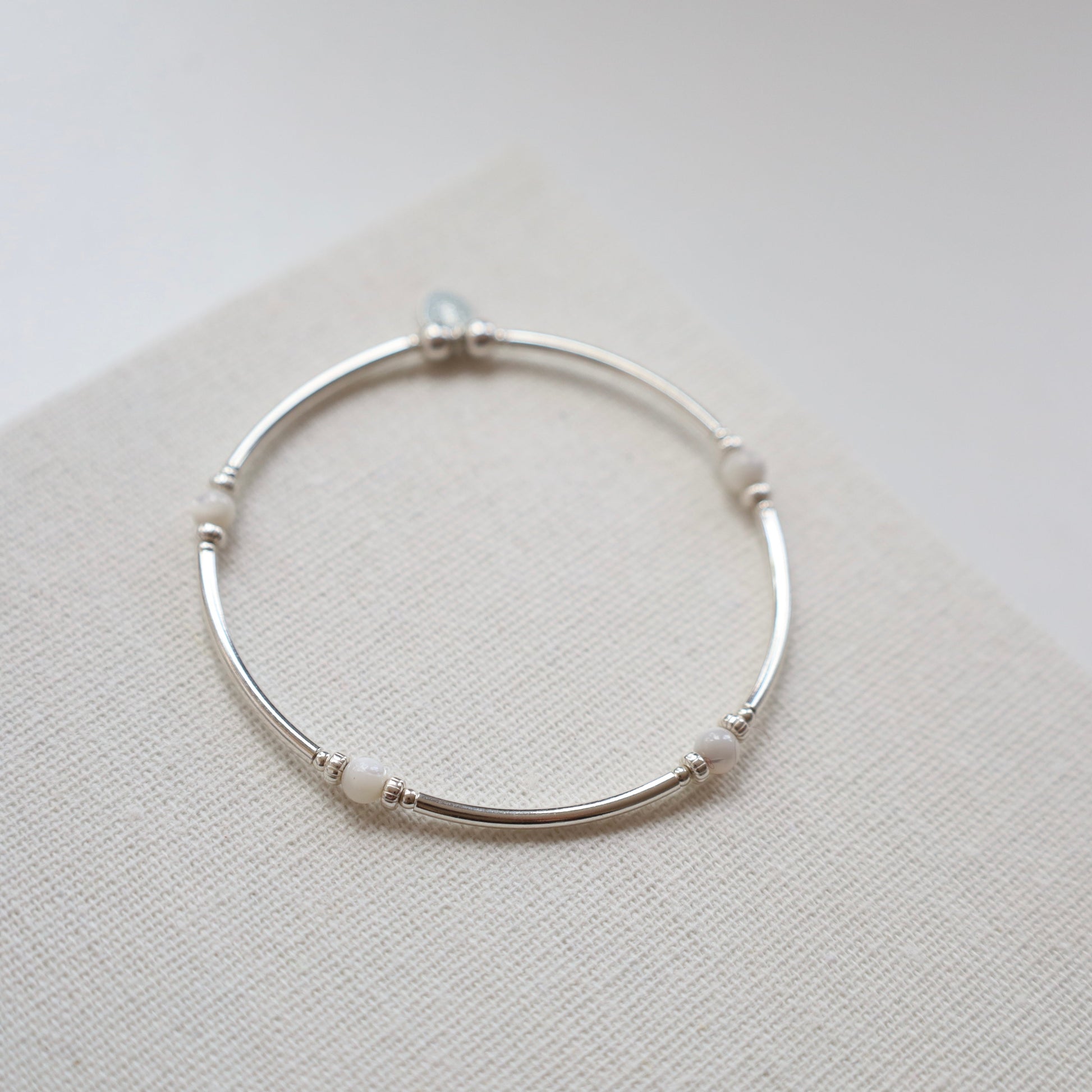 Silver bracelet with small beads on a light gray background