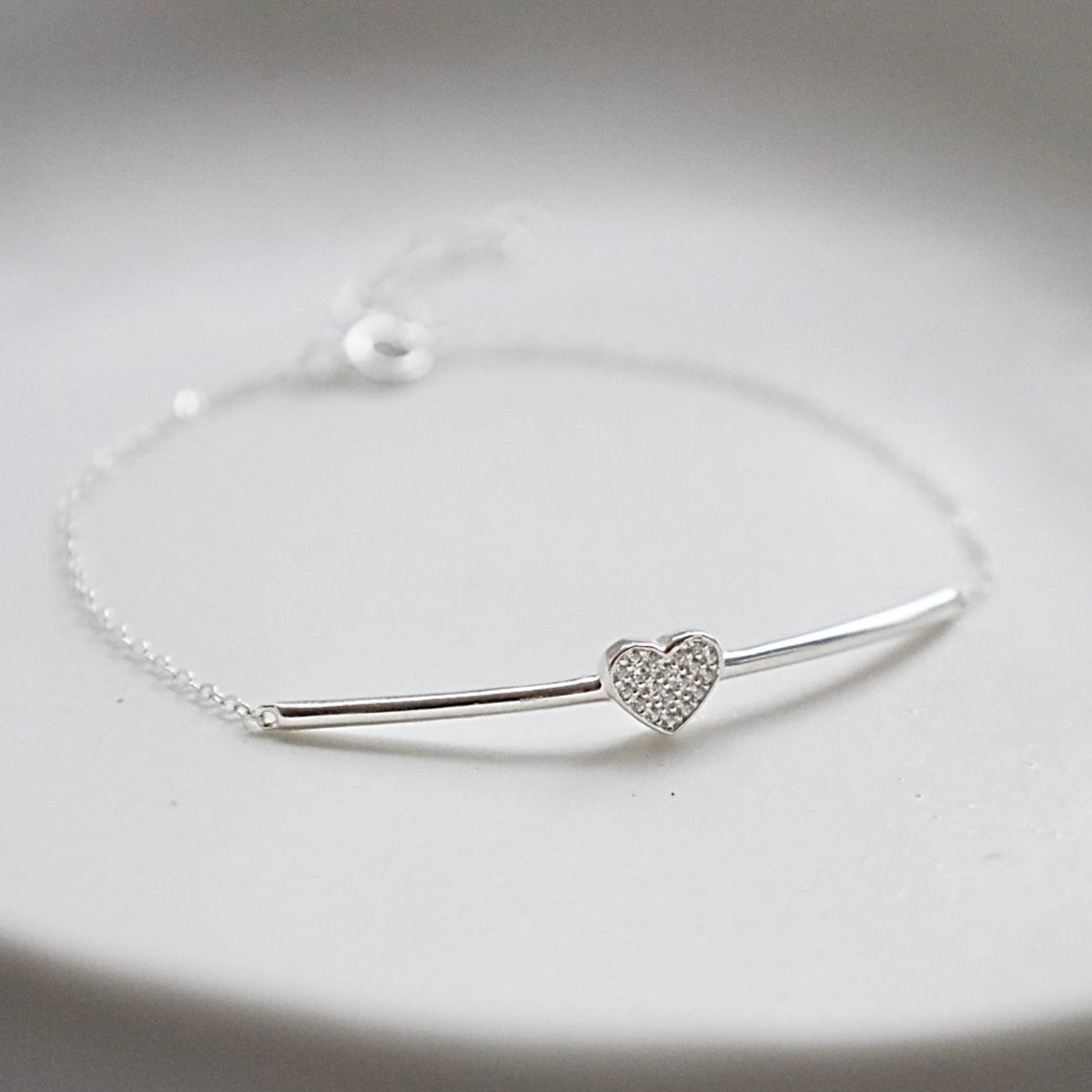 Silver bracelet with a heart-shaped details on a light gray background