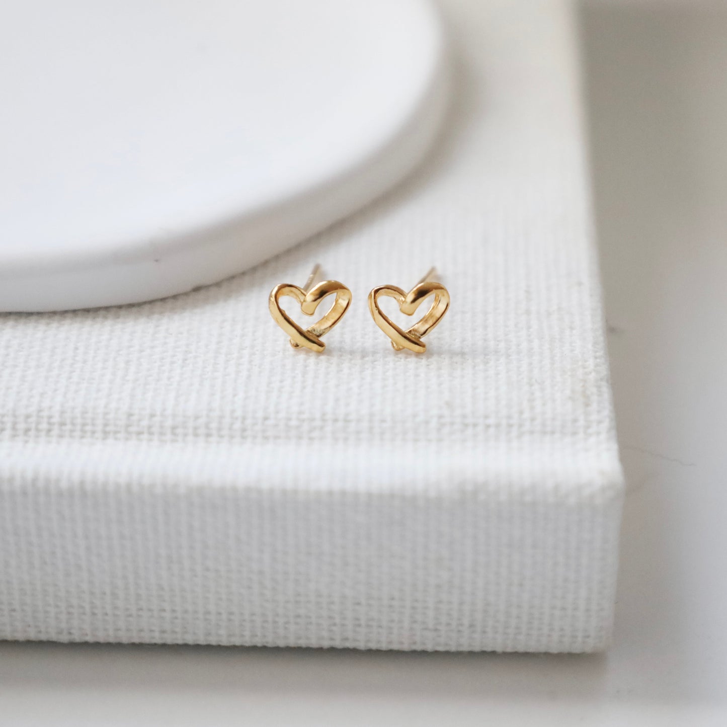Gold heart-shaped earrings on a white surface