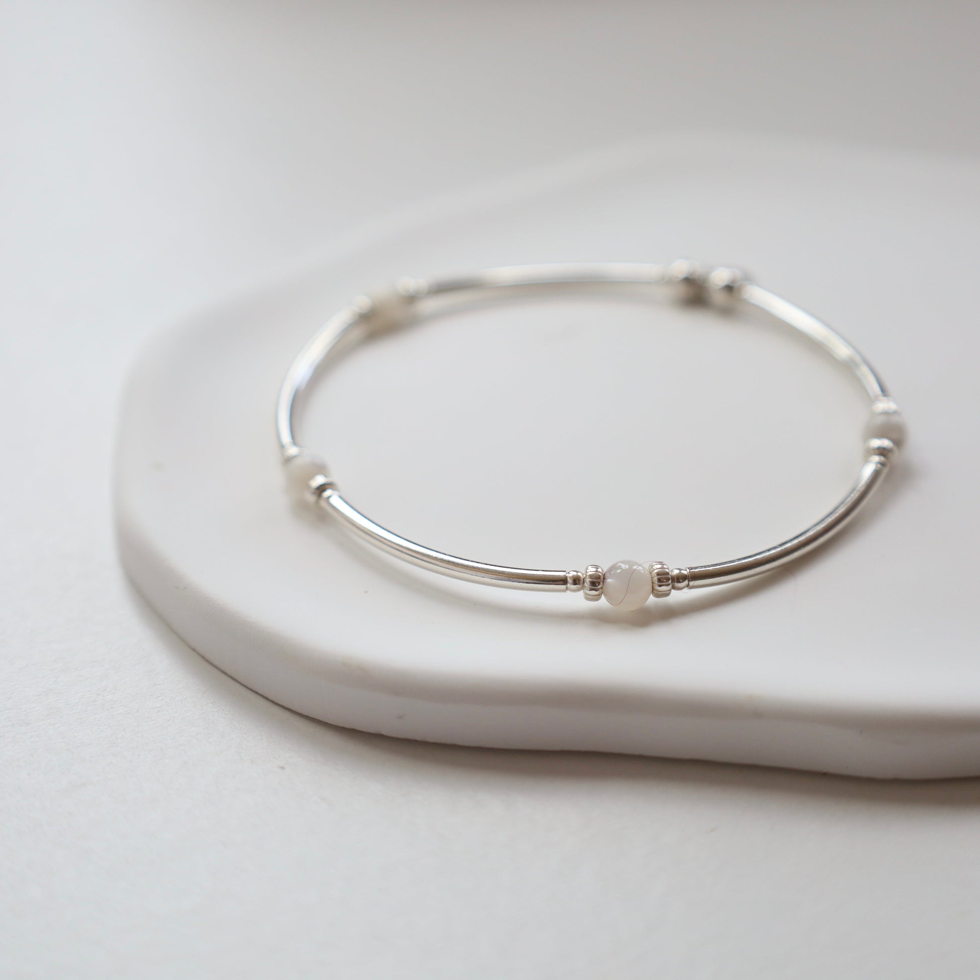 Silver bracelet on a white ceramic plate