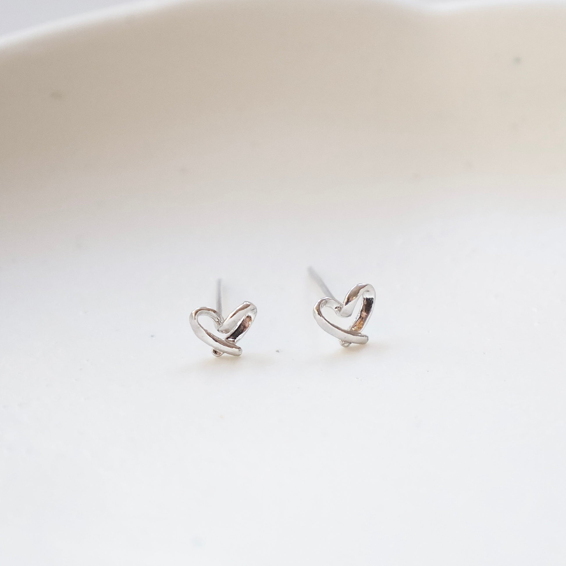 Heart-shaped silver earrings on a white background