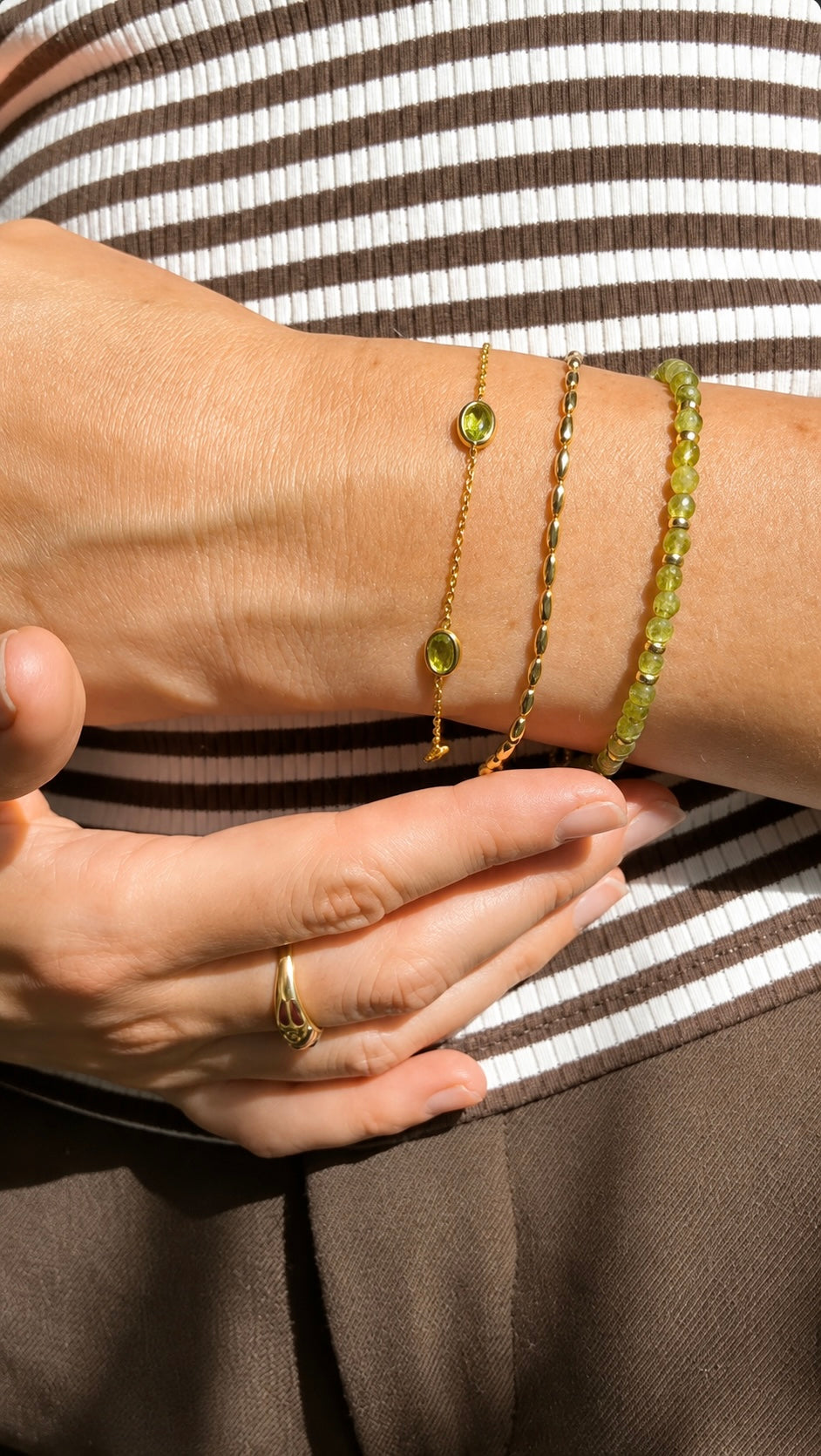 Gold peridot bracelet stack featuring a natural gemstone adjustable bracelet worn on the wrist.