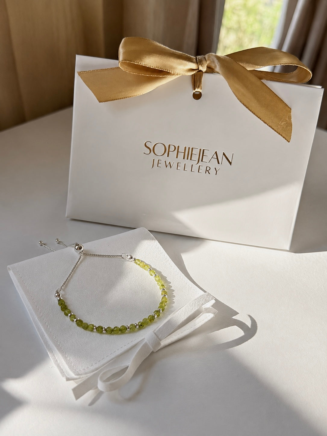 Silver adjustable peridot birthstone bracelet presented with a SophieJean Jewellery gift bag and white jewellery pouch.