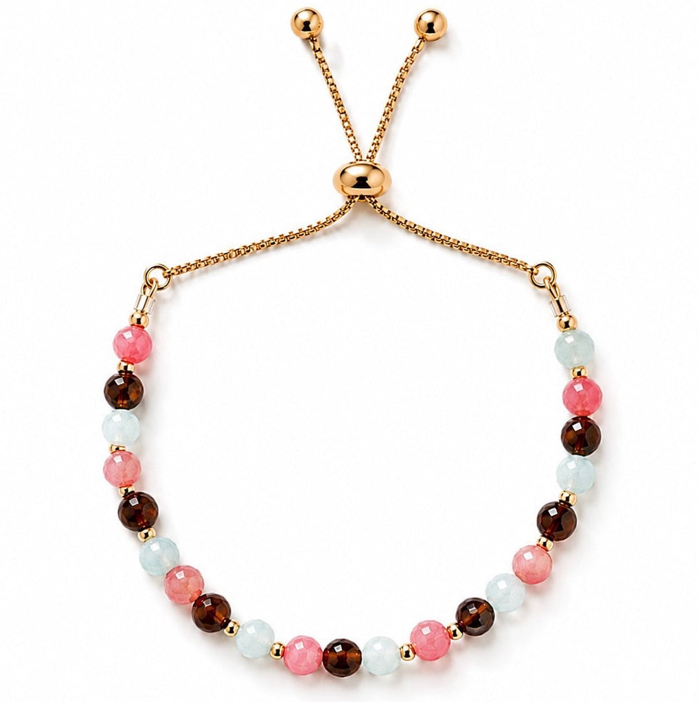 Mixed gemstone adjustable bracelet featuring pink coral, aquamarine and brown agate gemstones on a gold adjustable slider chain. Everyday summer jewellery with a minimalist white background.