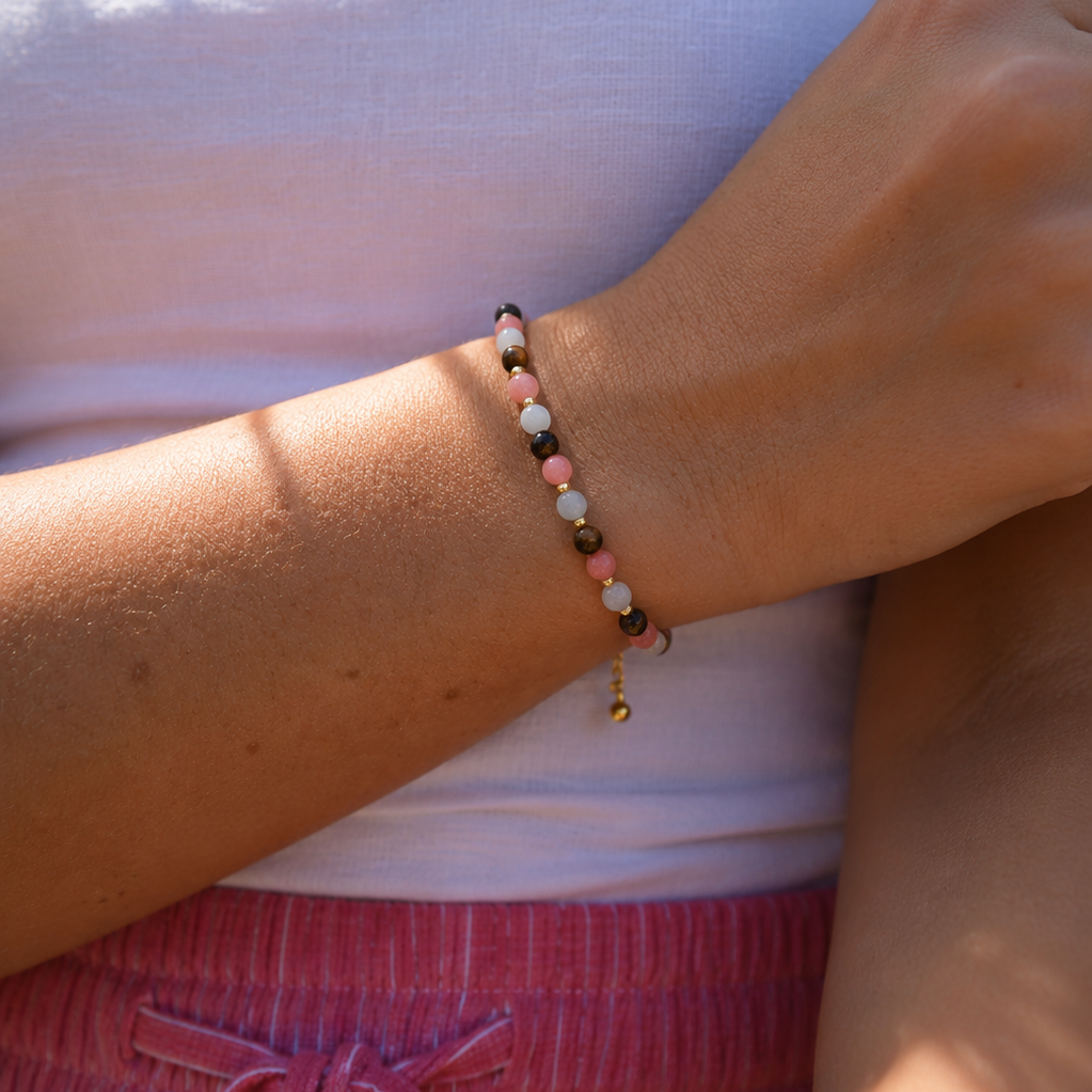 Gold adjustable mixed gemstone bracelet featuring pink coral, aquamarine and brown agate gemstones worn on the wrist with a summer outfit.